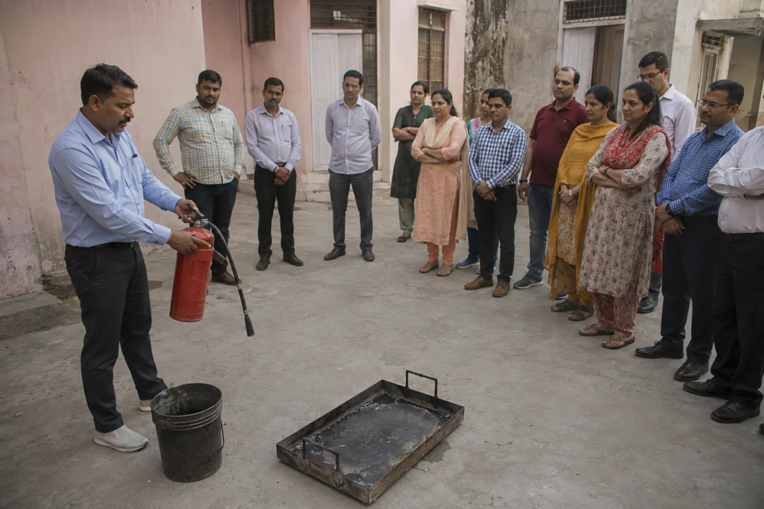 Illustration: an instructor demonstrating a fire extinguisher to a group in a courtyard