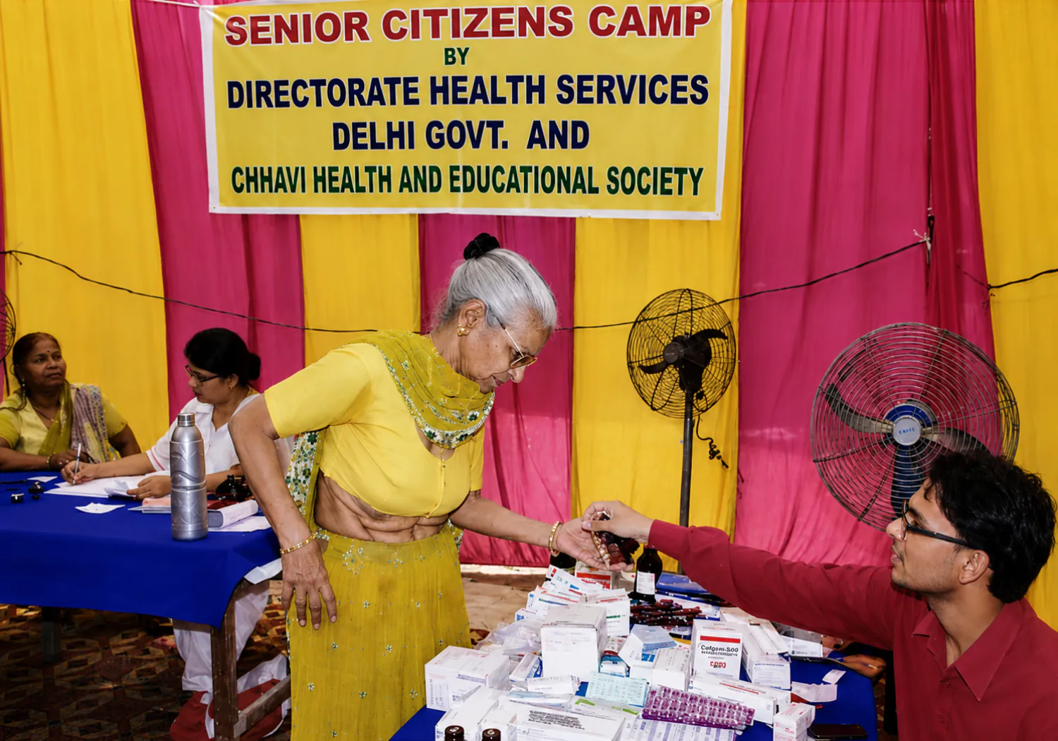 CHES staff dispensing medicines to an elderly woman at a senior citizens health camp