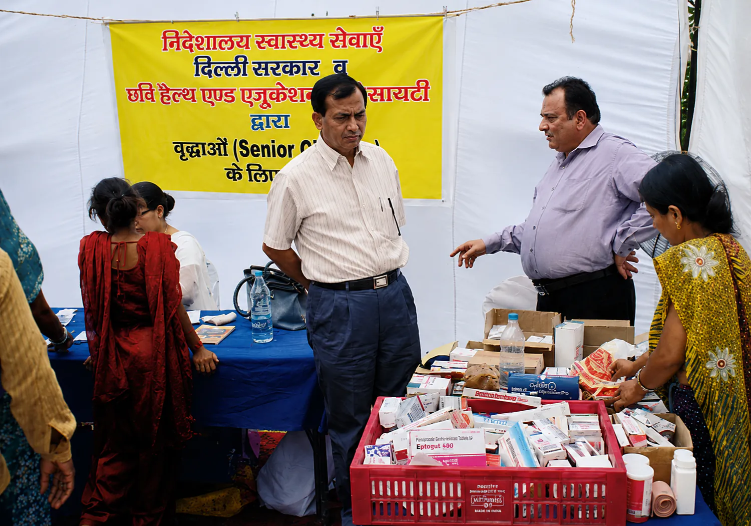 A CHES health camp with women and children waiting to be seen by a clinician